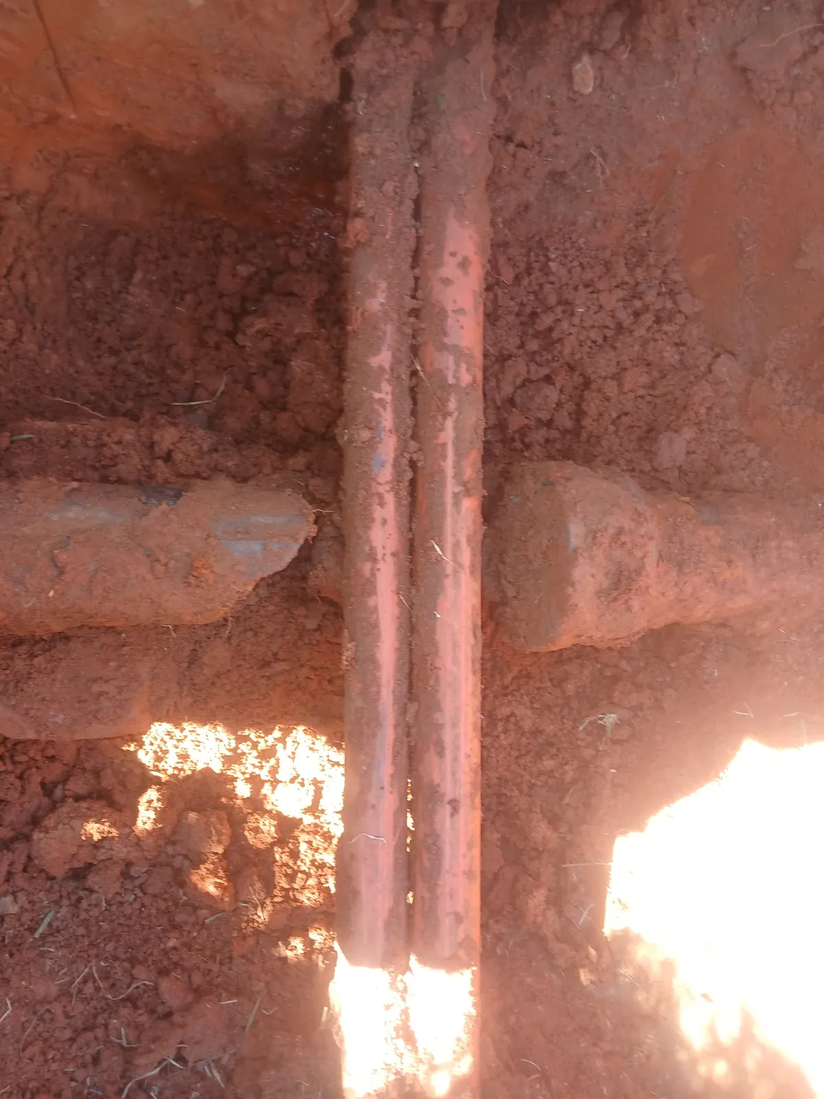 Old buried water lines exposed in red clay to find the leak, by Thomas Plumbing & Construction